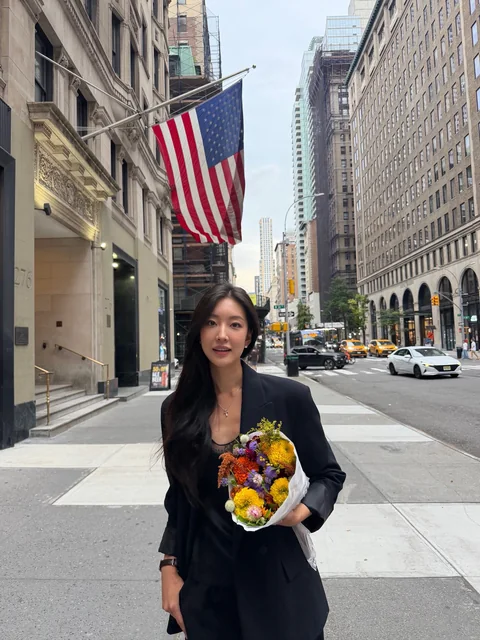 Yeaji in a black suit holding flowers on a Manhattan street