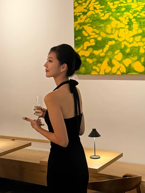 Yeaji in a black dress beside a green and yellow painting in Manhattan